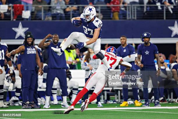 Jake Ferguson of the Dallas Cowboys runs the ball and jumps over Jason Pinnock of the New York Giants at AT&T Stadium on November 24, 2022 in...