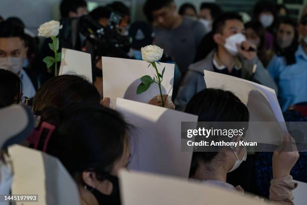 People hold sheets of blank paper in protest of COVID restriction in mainland as police setup cordon during a vigil in the central district on...