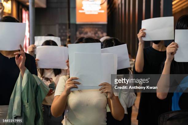 People hold sheets of blank paper in protest of COVID restriction in mainland as police setup cordon during a vigil in the central district on...