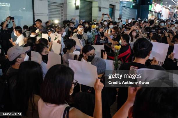 People hold sheets of blank paper and flower in protest of COVID restriction in mainland as police setup cordon during a vigil in the central...