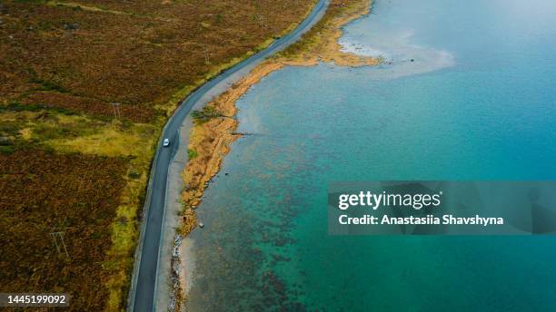 aerial view of a car driving the coastal road by emerald green sea in norway - smaragdgroen stockfoto's en -beelden