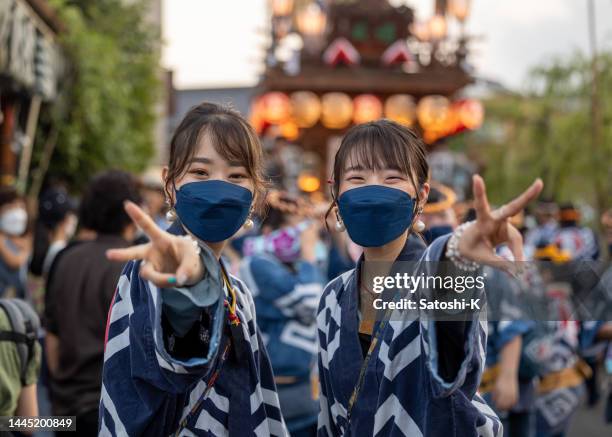 young woman in traditional japanese matsuri clothing looking at camera and making a peace sign in matsuri - matsuri stock pictures, royalty-free photos & images