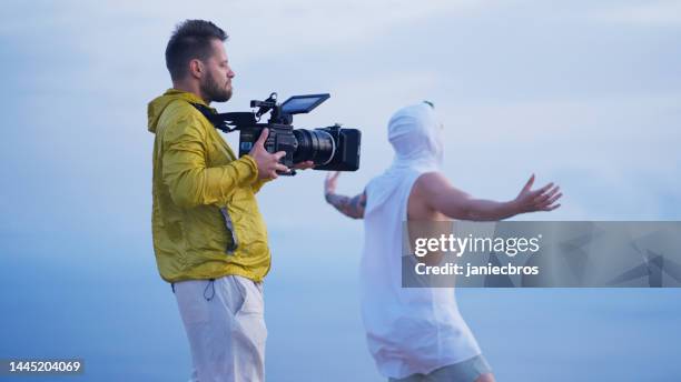 mann mit kamera filmt einen film auf einer klippe - film crew stock-fotos und bilder