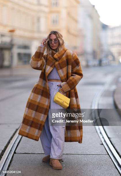 Karin Teigl is seen wearing Miu Miu lilac sunglasses, Rotate cropped lilac knit logo sweater, Chanel yellow leather bag, Henrik Vibskov checked brown...