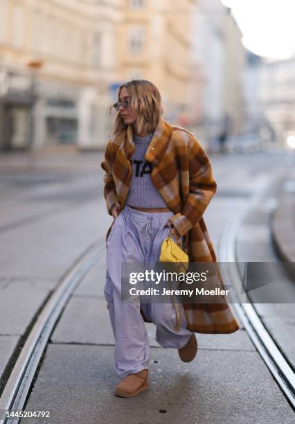 Karin Teigl is seen wearing Miu Miu lilac sunglasses, Rotate cropped lilac knit logo sweater, Chanel yellow leather bag, Henrik Vibskov checked brown...