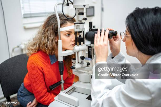 ophtalmologiste effectuant un examen de la vue avec un équipement optique sur une patiente - ophtalmologie photos et images de collection