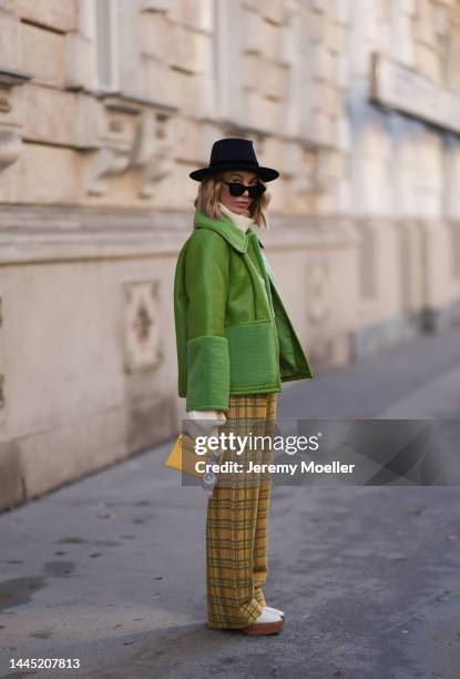 Karin Teigl is seen wearing Nomad Modern hat, Rhude black sunglasses, Hermès yellow leather mini Kelly, Baum & Pferdgarten green leather jacket,...