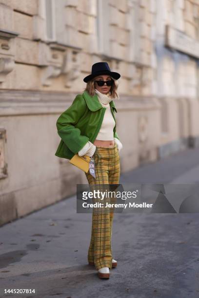 Karin Teigl is seen wearing Nomad Modern hat, Rhude black sunglasses, Hermès yellow leather mini Kelly, Baum & Pferdgarten green leather jacket,...