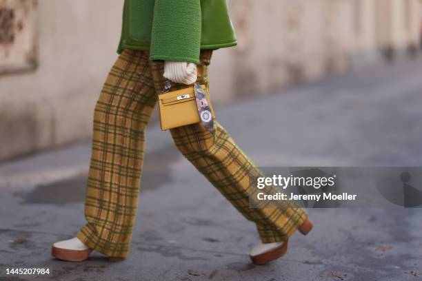 Karin Teigl is seen wearing Hermès yellow leather mini Kelly, Baum & Pferdgarten green leather jacket, Lumina beige cropped turtleneck sweater,...