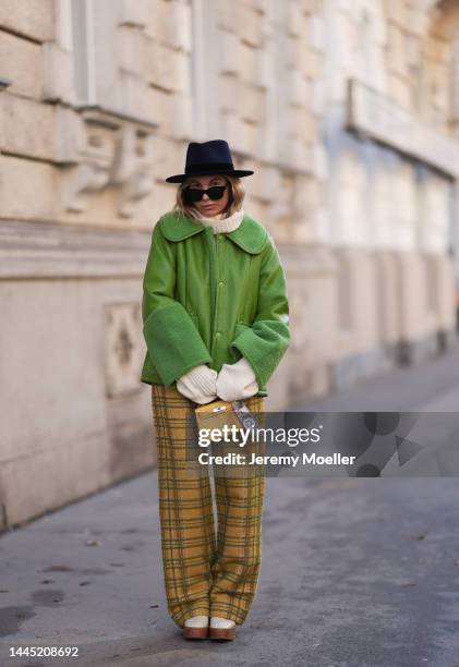 Karin Teigl is seen wearing Nomad Modern hat, Rhude black sunglasses, Hermès yellow leather mini Kelly, Baum & Pferdgarten green leather jacket,...