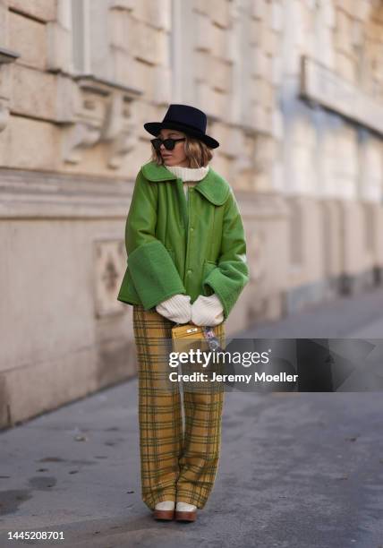 Karin Teigl is seen wearing Nomad Modern hat, Rhude black sunglasses, Hermès yellow leather mini Kelly, Baum & Pferdgarten green leather jacket,...