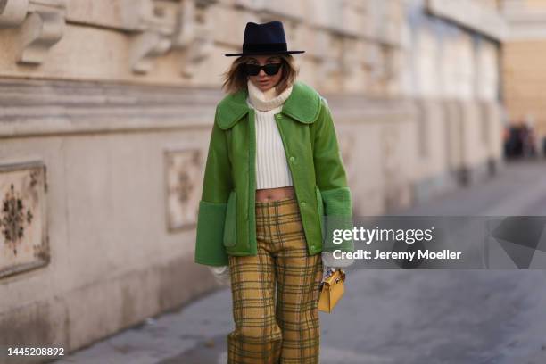 Karin Teigl is seen wearing Nomad Modern hat, Rhude black sunglasses, Hermès yellow leather mini Kelly, Baum & Pferdgarten green leather jacket,...