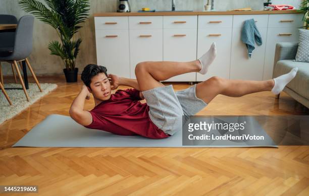 young man training at home - sit ups stockfoto's en -beelden