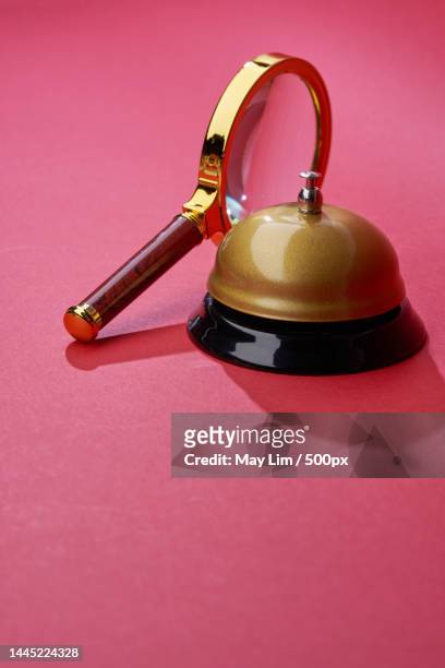 magnifying glass and service bell against red background,malaysia - hand bell stock pictures, royalty-free photos & images