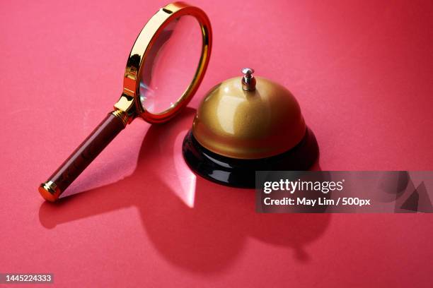 magnifying glass and service bell against red background,malaysia - hand bell stock pictures, royalty-free photos & images