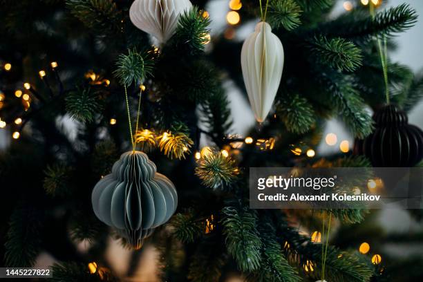 scandinavian christmas paper honeycomb ornament on christmas tree with lights. modern christmas decoration. - paper decoration stock-fotos und bilder