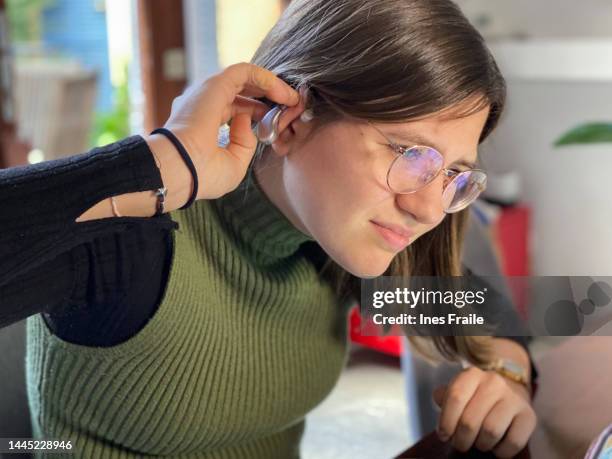 girl gesturing for not hearing well with hearing aid in her ear - hearing aids stock pictures, royalty-free photos & images