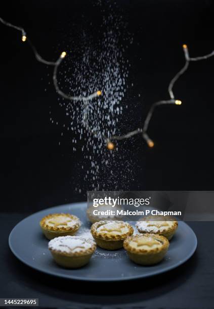 christmas mince pies with lights and icing (powdered) sugar snow - christmas mince pies stock-fotos und bilder