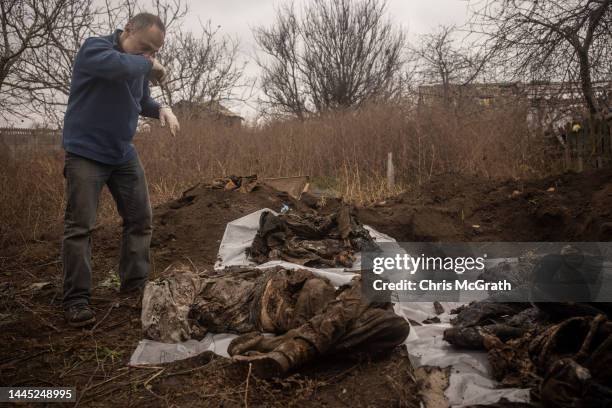 Forensic expert, Doctor Ihor Motrich looks over the exhumed remains recovered from a burial site containing the bodies of six civilians that were...