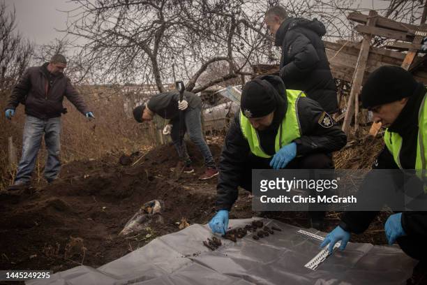 Police record bones as local residents help police, forensic experts and war crimes prosecution teams to exhume a burial site containing the bodies...