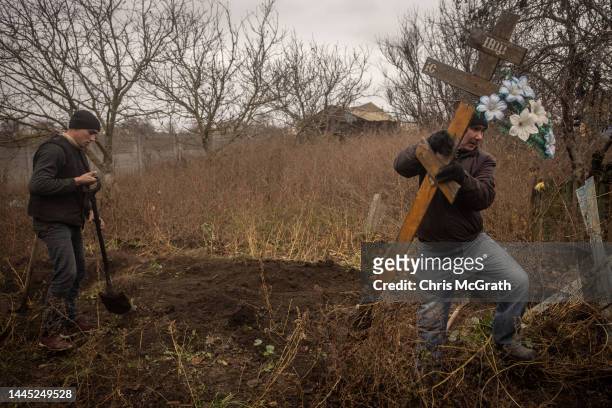 Local resident removes a cross from the a grave site as he helps police, forensic experts and war crimes prosecution teams exhume a burial site...