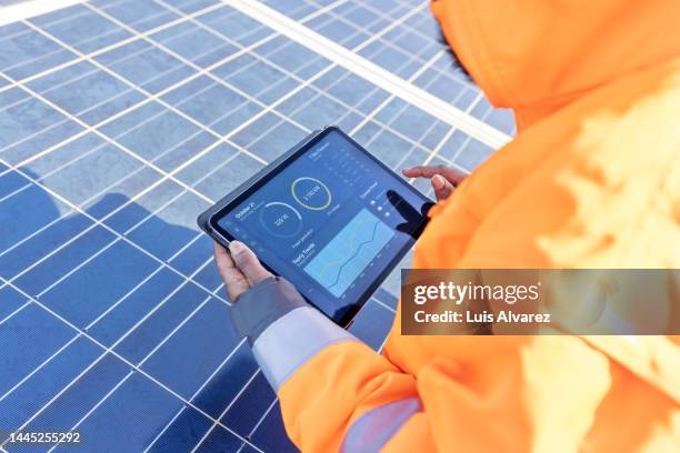 field technician running diagnostic tests on digital tablet at solar farm - energie sparen stock-fotos und bilder