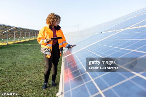 woman technician examining solar panels on grip - solar equipment stock-fotos und bilder