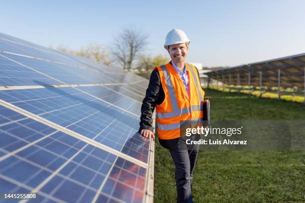 manager with reflecting clothing and hardhat at solar farm - leuchtbekleidung stock-fotos und bilder