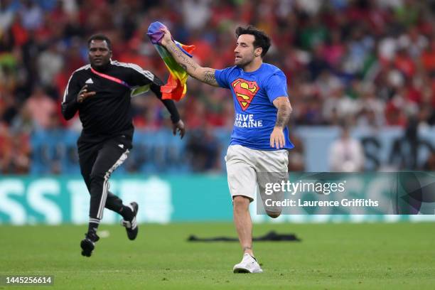 Pitch invader wearing a shirt reading "Save Ukraine" holds a rainbow flag during the FIFA World Cup Qatar 2022 Group H match between Portugal and...