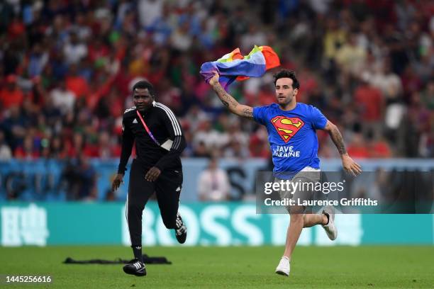 Pitch invader wearing a shirt reading "Save Ukraine" holds a rainbow flag during the FIFA World Cup Qatar 2022 Group H match between Portugal and...