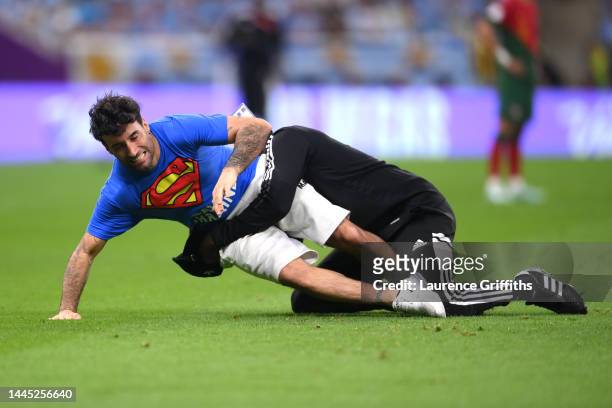 Pitch invader wearing a shirt reading "Save Ukraine" is apprehended by security during the FIFA World Cup Qatar 2022 Group H match between Portugal...