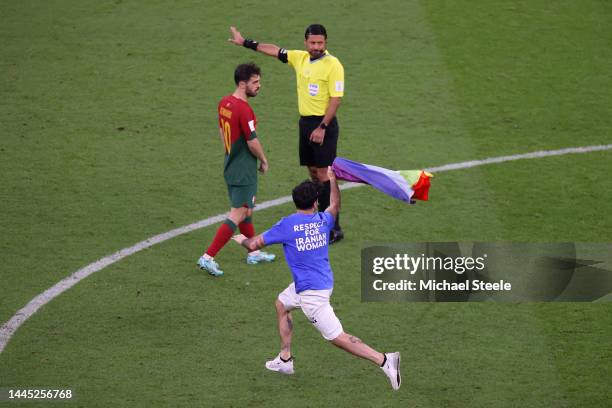 Pitch invader wearing a shirt reading "Respect for Iranian woman" holds rainbow flag during the FIFA World Cup Qatar 2022 Group H match between...