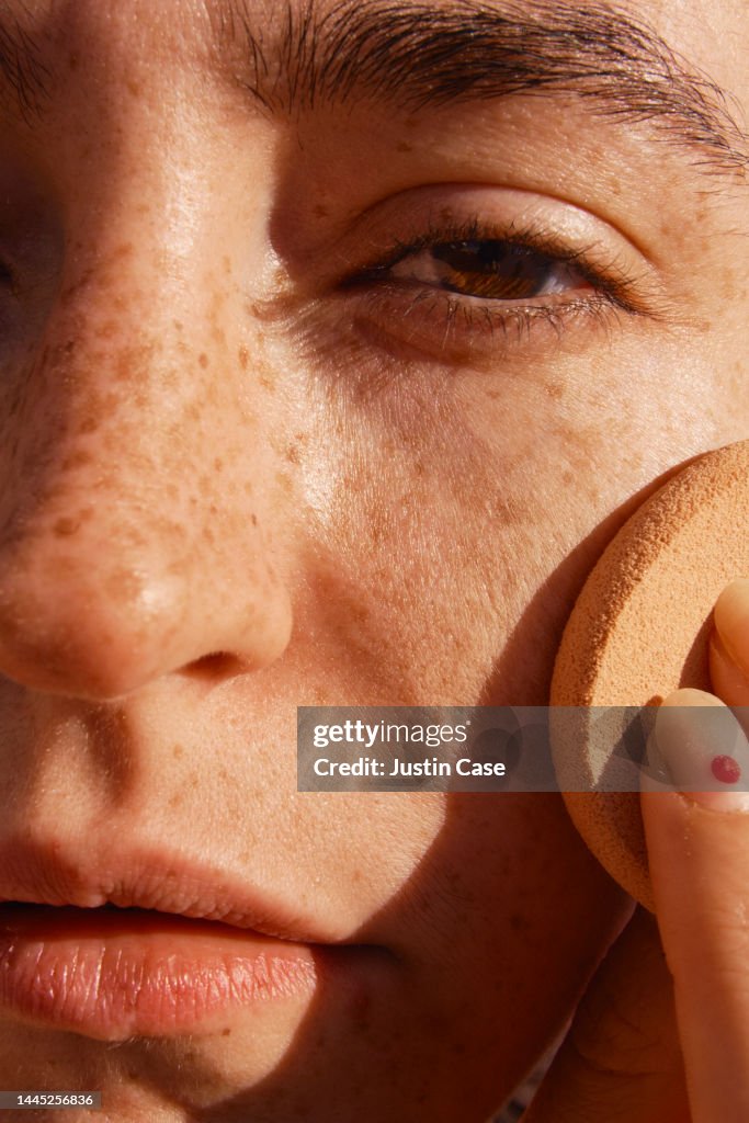 Close up of a woman's face applying make-up