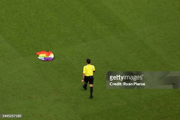 Referee Alireza Faghani walks to pick up a rainbow flag on the pitch after a pitch invader is held during the FIFA World Cup Qatar 2022 Group H match...