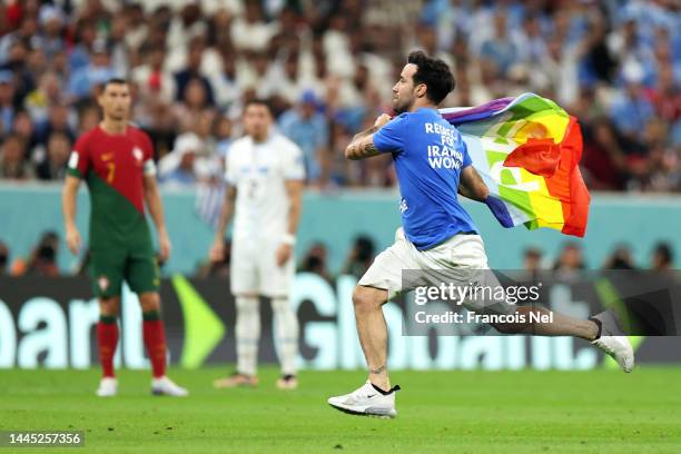 Pitch invader wearing a shirt reading "Respect for Iranian woman" holds a rainbow flag during the FIFA World Cup Qatar 2022 Group H match between...