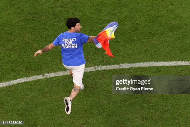 Pitch invader wearing a shirt reading "Respect for Iranian woman" holds a rainbow flag during the FIFA World Cup Qatar 2022 Group H match between...