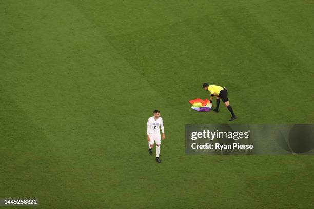 Referee Alireza Faghani picks up a rainbow flag on the pitch after a pitch invader is held during the FIFA World Cup Qatar 2022 Group H match between...