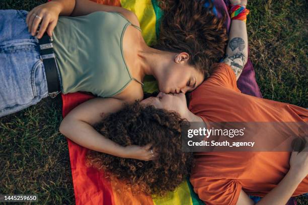 couple lying on pride flag - photos of lesbians kissing stock pictures, royalty-free photos & images