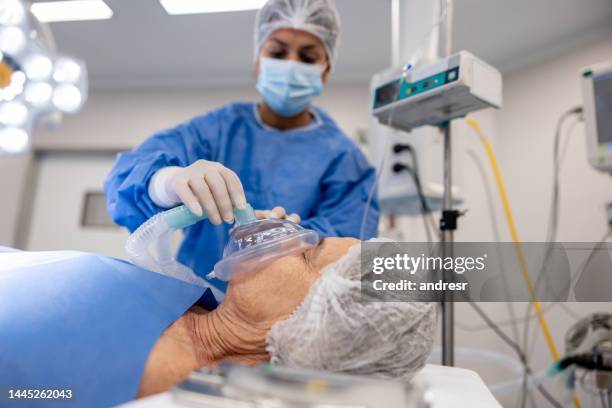 arzt legt einem patienten unter narkose im krankenhaus eine sauerstoffmaske auf - oxygen mask stock-fotos und bilder