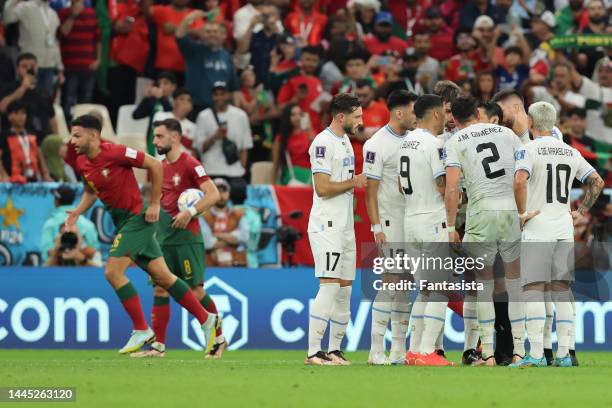 Bruno Fernandes of Portugal carries the ball towards the spot as Uruguay player protest to the Referee Alireza Faghani of Iran after he awarded a...