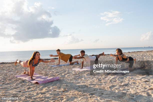 lehrer und drei schüler machen yoga am strand - beach yoga stock-fotos und bilder