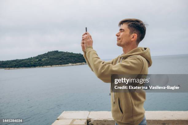 a man taking pictures on a mobile phone of the views of dubrovnik on a trip - croatia tourist stock pictures, royalty-free photos & images