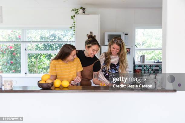 three young women preparing  food in the kitchen - mount maunganui 個照片及圖片檔