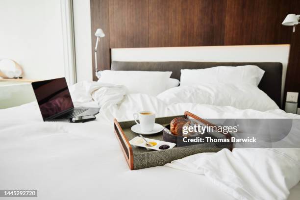 medium shot of room service tray and computer on unmade bed in hotel - quarto de hotel imagens e fotografias de stock