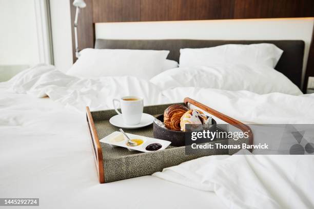 medium shot of room service tray with breakfast on unmade bed in hotel - bedroom suite stock-fotos und bilder