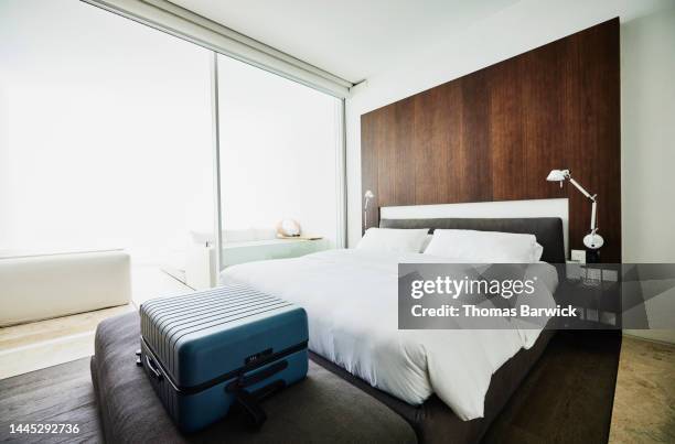 wide shot of suitcase at end of bed in luxury hotel room - quarto-de-hotel imagens e fotografias de stock