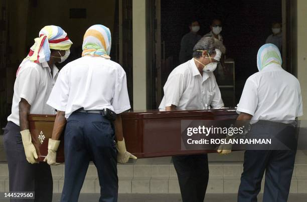 Undertakers with faces fully covered carry the coffin of the Singapore pastor who died of Severe Acute Respiratory Syndrome to be cremated in...
