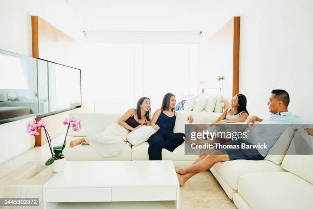 wide shot of family relaxing in luxury hotel suite while on vacation - asian man suite stock-fotos und bilder