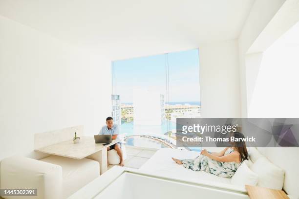 wide shot of couple relaxing on deck of suite at tropical resort - elegant couple ストックフォトと画像