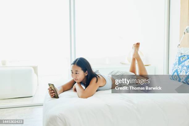 wide shot of girl looking at smart phone while relaxing in hotel room - une seule adolescente photos et images de collection